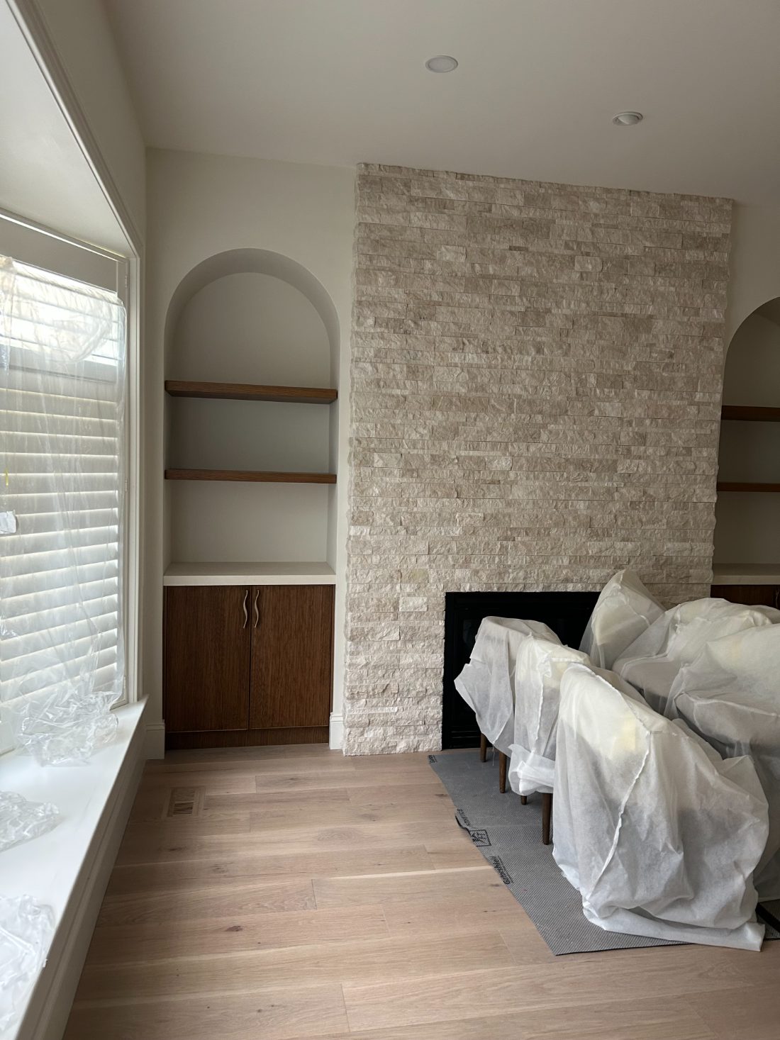 Great room with stacked-stone fireplace and arched built-ins, mid-build
